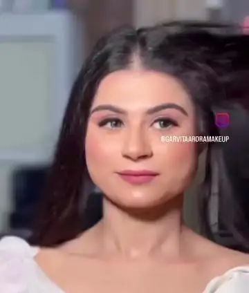 A woman in a white outfit with soft pink makeup and loose hair, a light, minimal look.